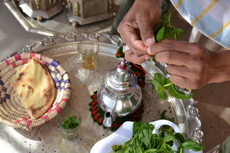 Pouring Moroccan mint tea with fresh bread on a Berber tray