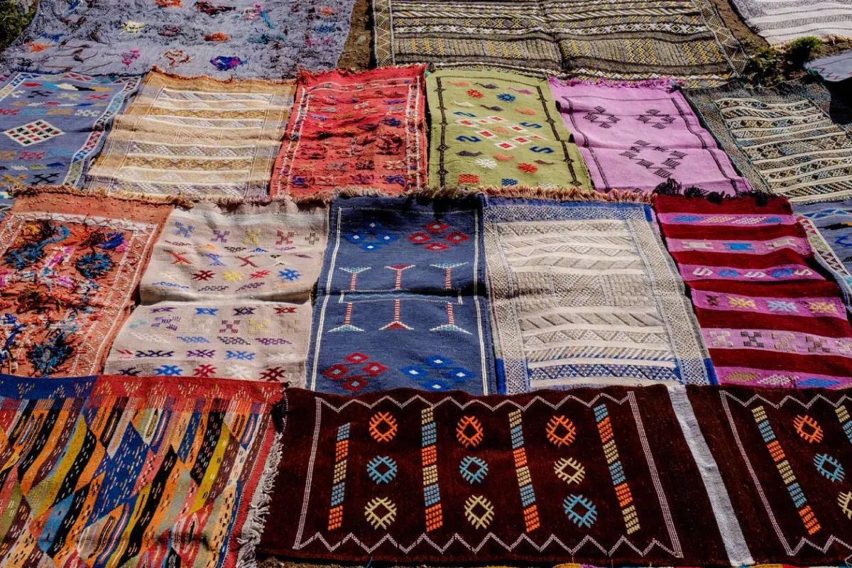 Handwoven Berber rugs spread out side by side on the ground