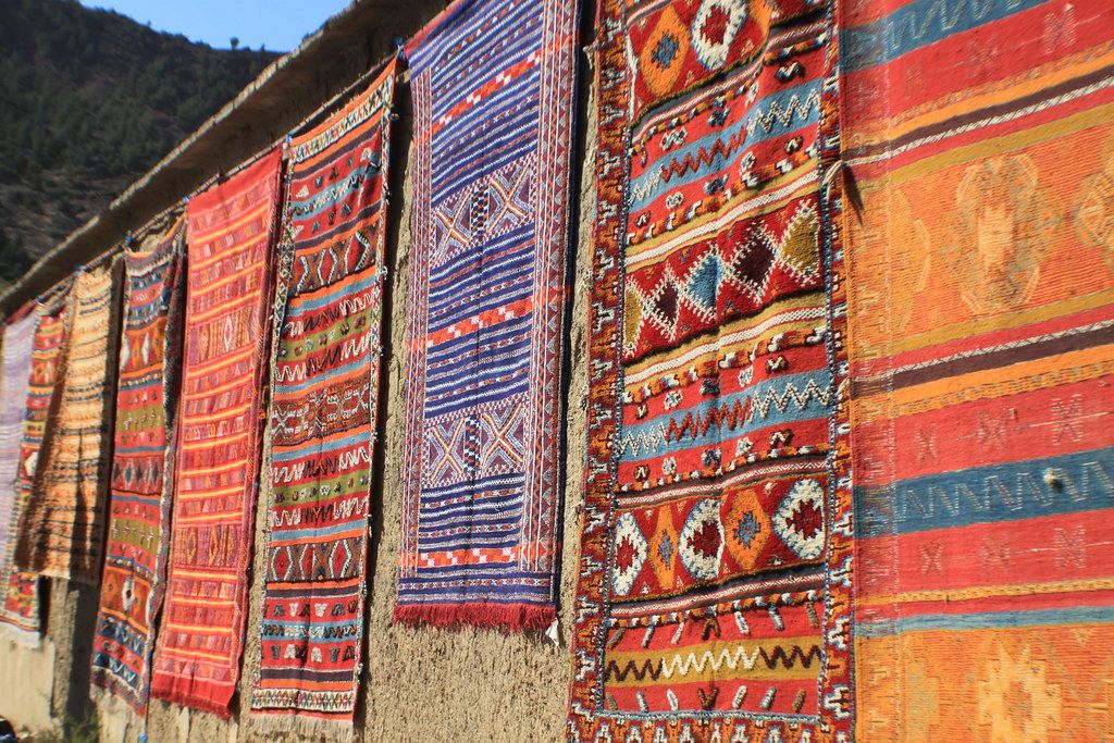 Colourful Berber rugs hanging on an earth wall in the sun